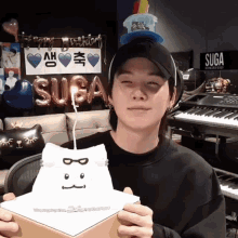a person holding a cake with a candle and a sign that says suga on it