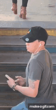 a man wearing a hat and ear buds is looking at his cell phone