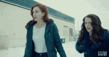 two women walking in the snow with the letters hhw on the bottom right