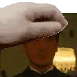 a man wearing a tuxedo and a towel on his head is being touched by a hand .