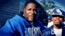 two men are standing next to each other and one of them is wearing a blue jacket that says aokbn on it