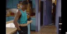 a man is standing in a kitchen wearing boxing gloves and a belt with the letter b on it .