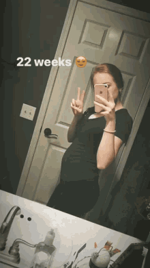 a woman is taking a picture of her belly in the mirror and the words 22 weeks are above her