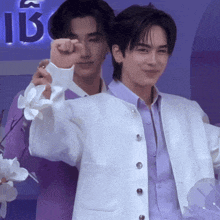 a man in a purple shirt and a man in a white jacket are standing next to each other