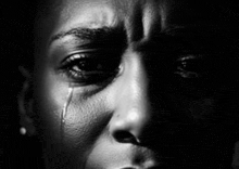 a black and white photo of a woman crying with a tear running down her face .