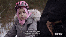 a little girl wearing a pink hijab and a helmet says we heard bigfoot was on the loose on the screen