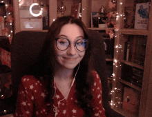 a woman wearing glasses sits in a chair in front of a bookshelf with a book titled " the hobbit " on it