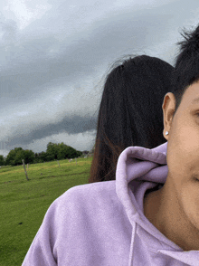 a woman in a purple hoodie is standing in a field
