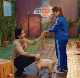 a man and a woman are petting a sheep in front of a sign that says home