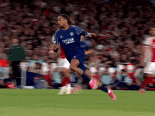 a soccer player wearing a blue qatar jersey runs on the field