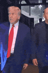 a man in a blue suit and tie is standing in front of a crowd