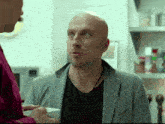 a bald man with a beard is talking to a woman