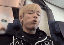 a man with blonde hair is sitting in front of an exit sign on a plane