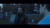 a man in a blue shirt is walking down a street with other people