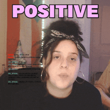 a woman with a bandana on her head stands in front of a poster that says positive
