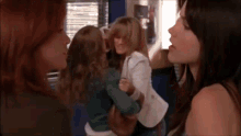 a group of women are standing next to each other in a room and one of them is holding a child .