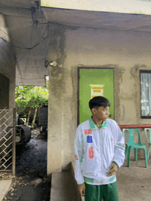 a man in a white jacket stands in front of a green door with a sign on it that says emergency