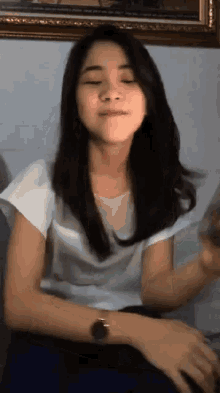 a woman wearing a white shirt and a watch is making a funny face