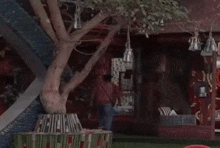 a man standing in front of a red building with a tree in the foreground