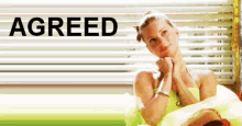 a woman is sitting in front of a window with the word agreed written on it