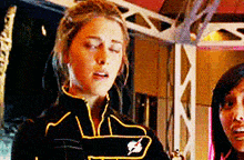 a woman in a black and yellow superhero costume is standing next to another woman in a room .