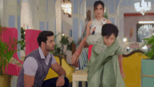a woman in a green saree is being held by a man in a gray vest