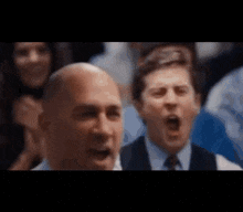 a man in a suit and tie is screaming in a crowd .