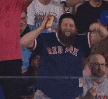 a man with a beard wearing a blue red sox jersey
