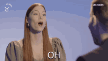 a woman with long red hair is talking to a man with elite daily written on the bottom