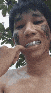 a man with braces on his teeth and a tattoo on his face looks at the camera