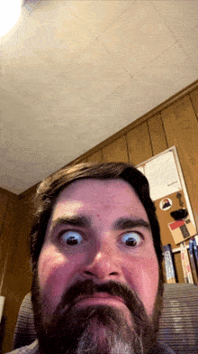 a man with a beard is making a funny face in front of a wood paneled wall