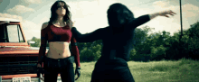 a woman in a red crop top is standing next to a woman in a black top with a texas license plate