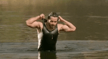 a man in a tank top is standing in the water .