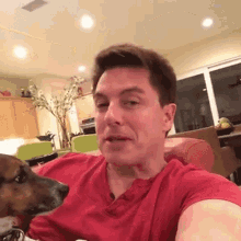 a man in a red shirt with a dog on his lap