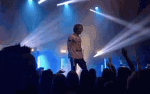 a man stands on stage with a microphone in front of a crowd