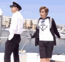 two people are standing next to each other on a boat in a marina .