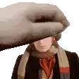a man wearing a scarf and hat is being touched by a large hand .