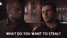 two men are standing next to each other in a bar and talking to each other .