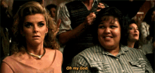 two women are sitting in a crowd and one of them says oh my god