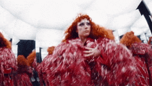 a woman with red hair and a red dress is standing in front of a mirror