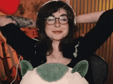 a woman wearing headphones and glasses is sitting on a stuffed animal .