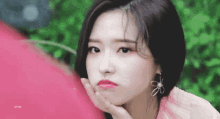 the girl is wearing a pink dress and earrings and is making a funny face .