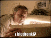 a man looking into a fridge with the words " z biedronki " written on the bottom