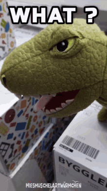 a stuffed dinosaur is sitting next to a box that says byggle