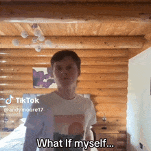 a man in a white shirt is standing in front of a log cabin and says what if myself