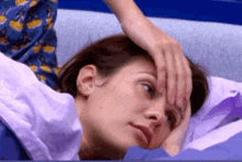 a woman is laying in bed with her hand on her forehead