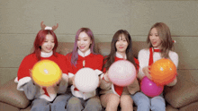 four girls are sitting on a couch and holding balloons