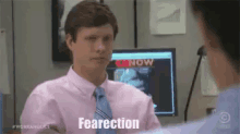 a man in a pink shirt and tie is talking to a woman in an office .