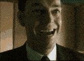 a man in a suit and tie is laughing with his mouth open