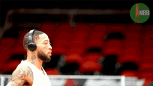 a basketball player wearing headphones stands in front of an empty nba stadium